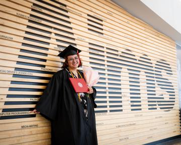 grad with a boquet and diploma in cap and gown