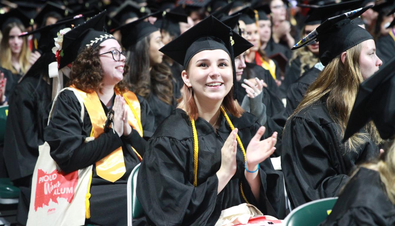 Aims graduates applauding their classmates during commencement ceremony. 