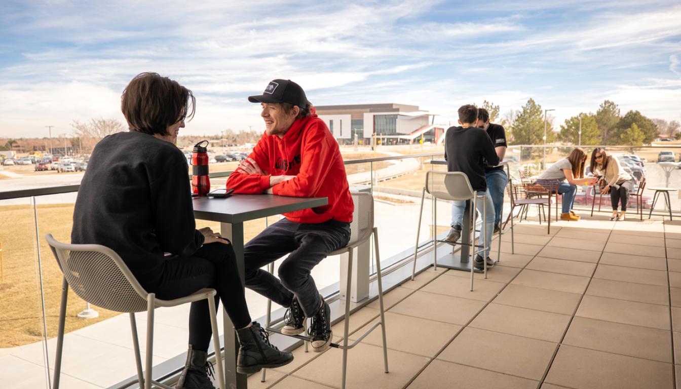 Students talking on the outside balcony of the Student Center at Aims Community College Greeley Campus