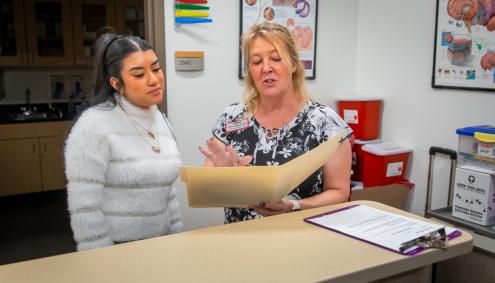 Two women looking at folder in medical clinic office