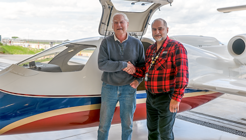 two men shaking hands in front of airplane