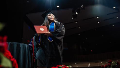 Aims Student in Gap and Gown with Diploma
