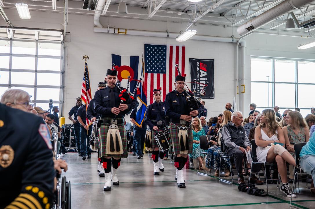 bagpipe players in a line with flags at Fire Academy Graduation