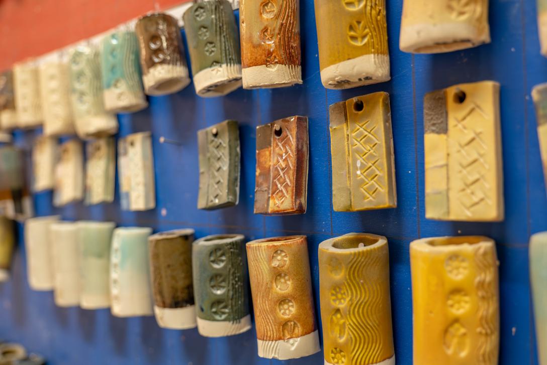 ceramic tiles with earth tone colored glazes hanging on blue wall