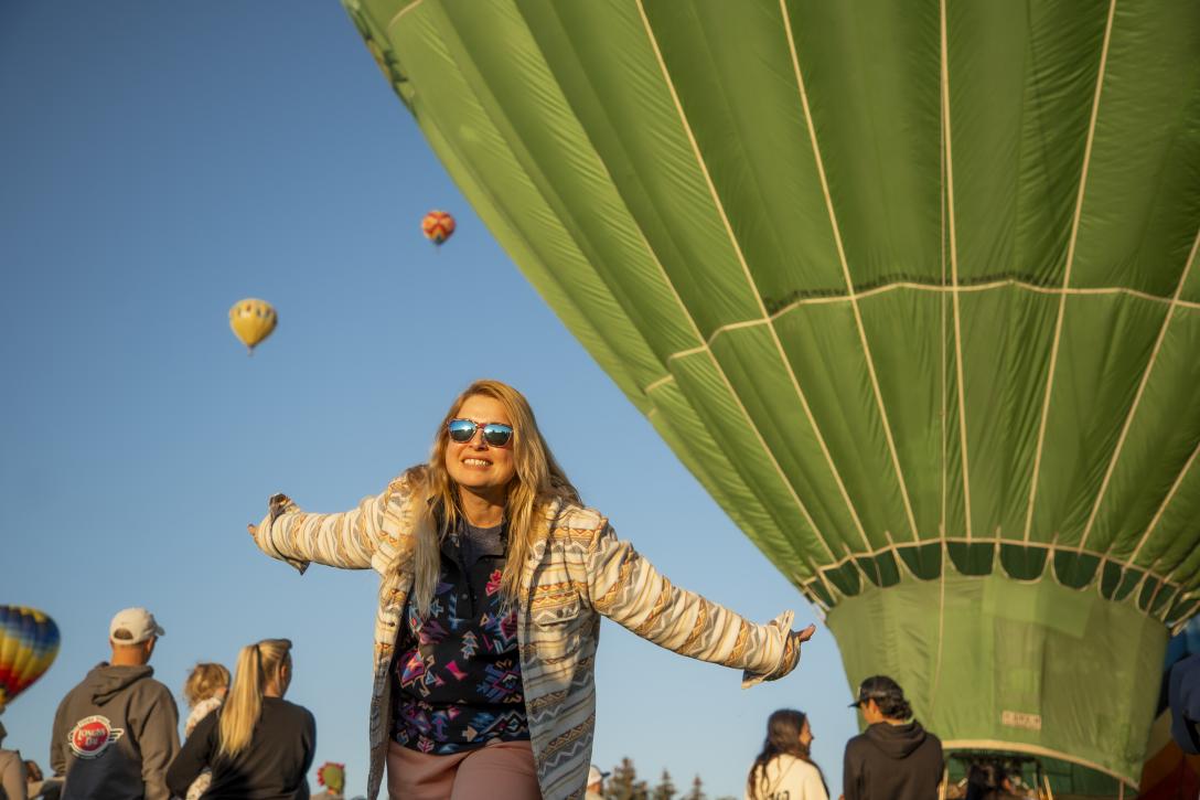 woman with arms out streached in front of hot air balloon