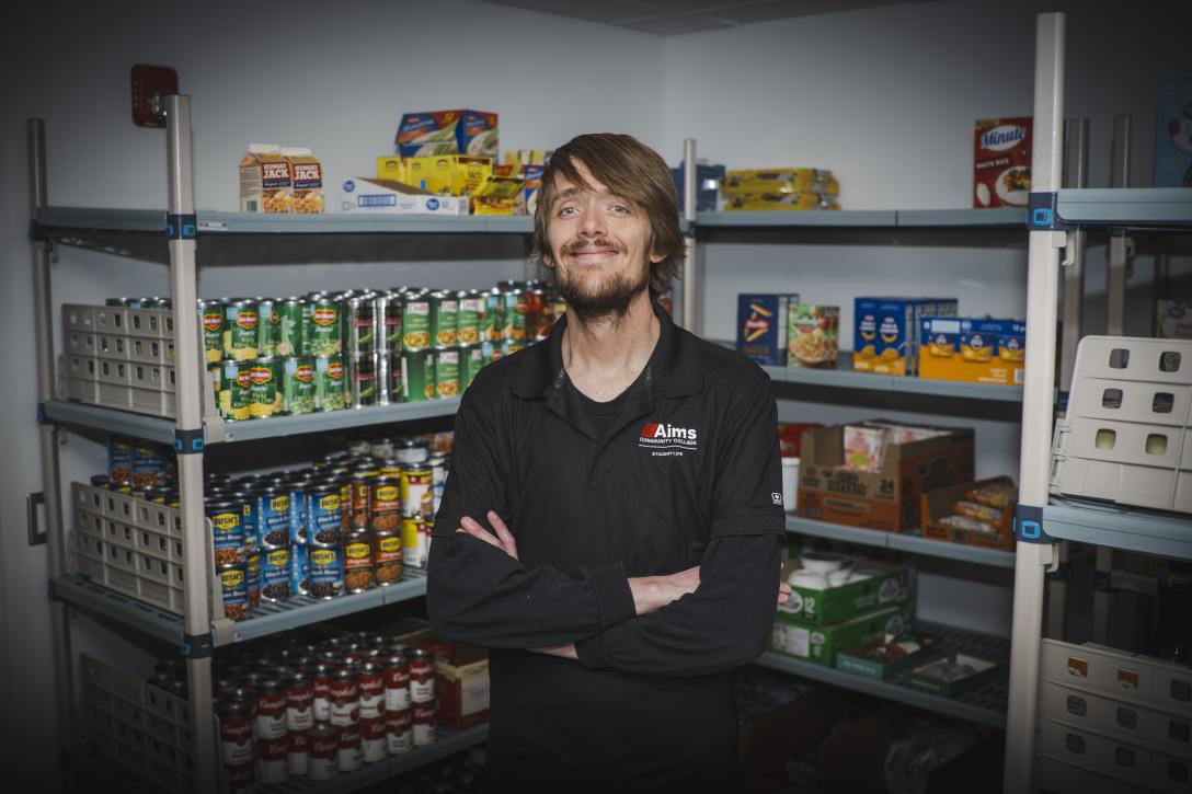 Jeff Thatch at Arty's Pantry with Shelves of Canned Food