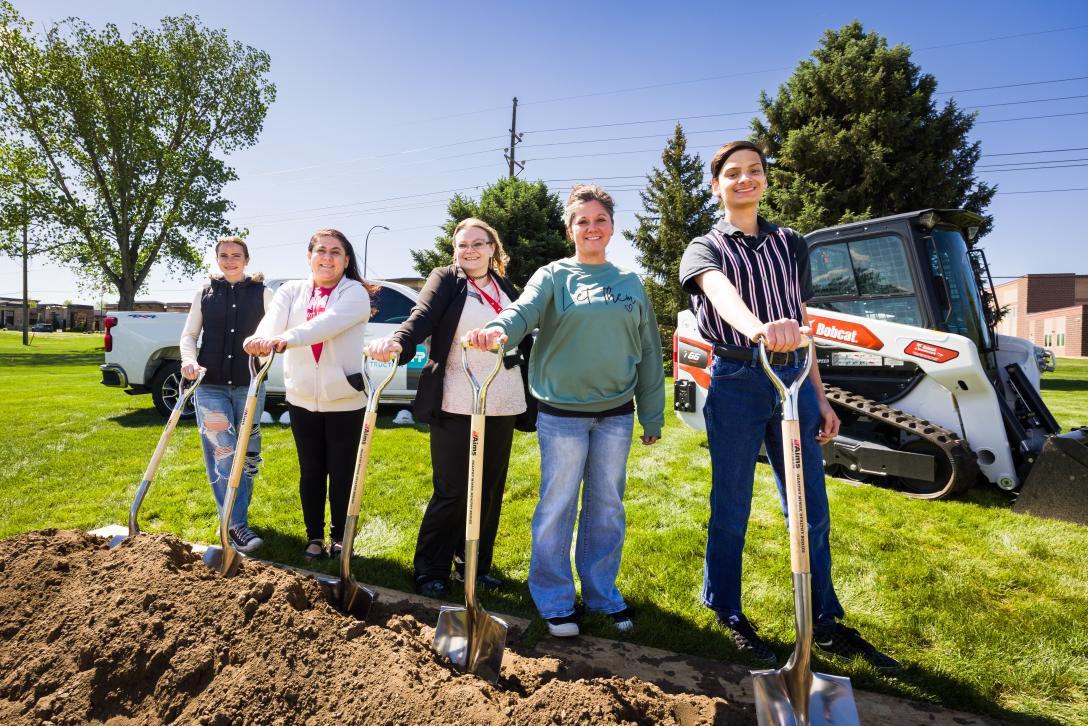 5 people standing with shovels at groundbreaking event