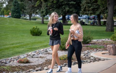 Two female students walking outdoors on the Aims Greeley Campus