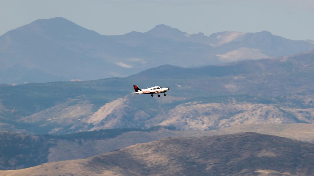 Aims airplane in flight in foothills