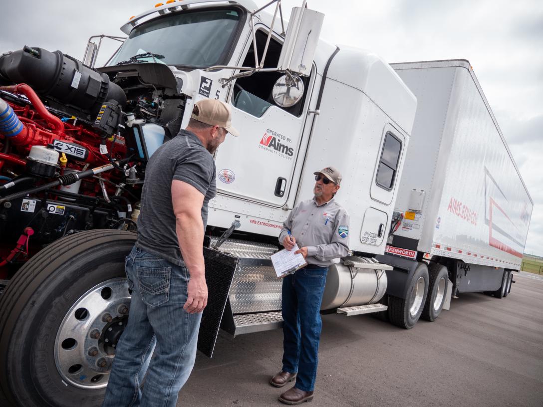 An Aims CDL student and instructor talking next to a semi truck in the CDL lot on the Fort Lupton campus