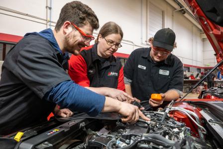 Instructor and students looking under the hood of a car