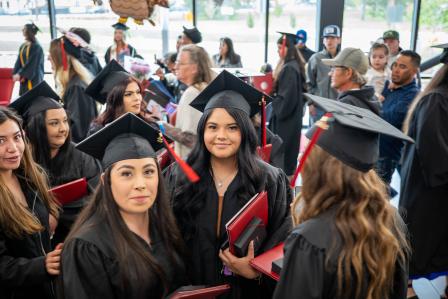Aims graduates in caps and gowns gather in the Welcome Center after spring 2023 commencement cermony